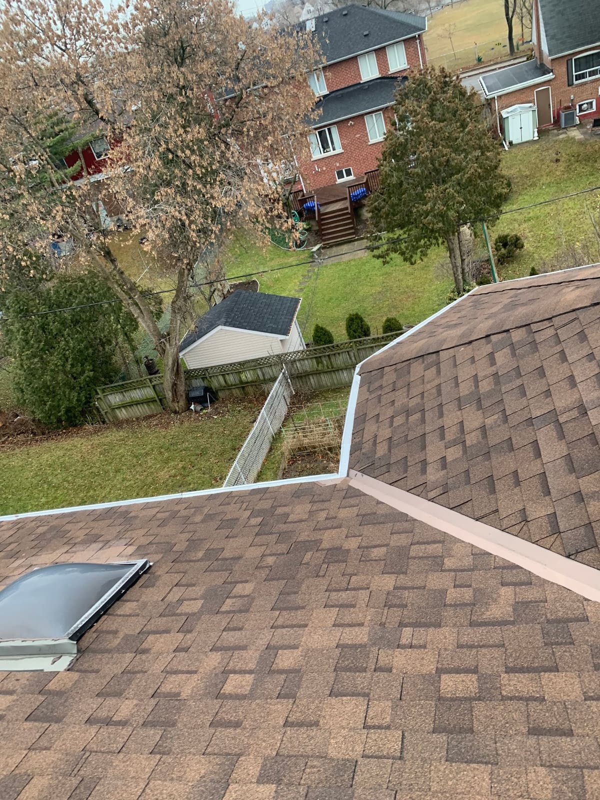 New brown architectural shingles with white eavestrough and a skylight