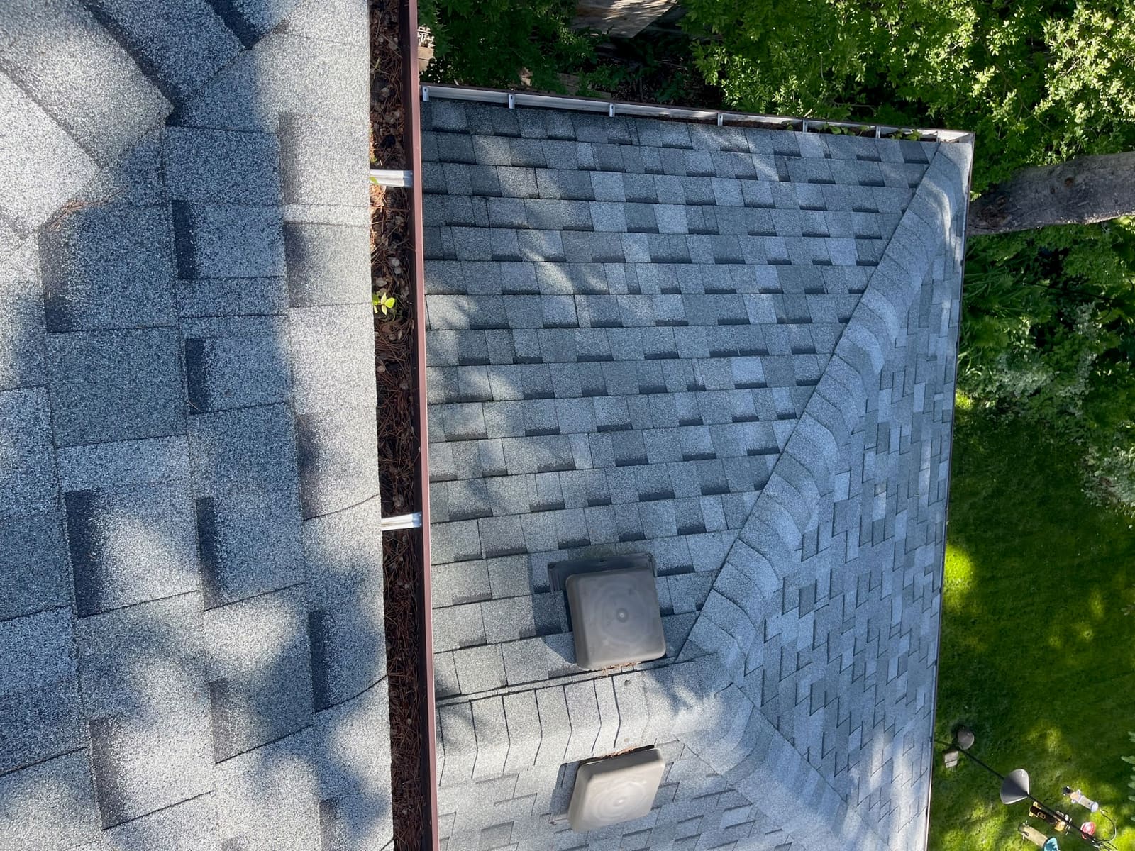 Grey architectural shingles, roof vents and brown eavestrough on a finished roof