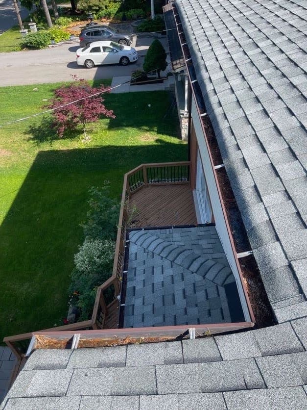 View from the roof of new grey shingles and eavestrough over a lower roof