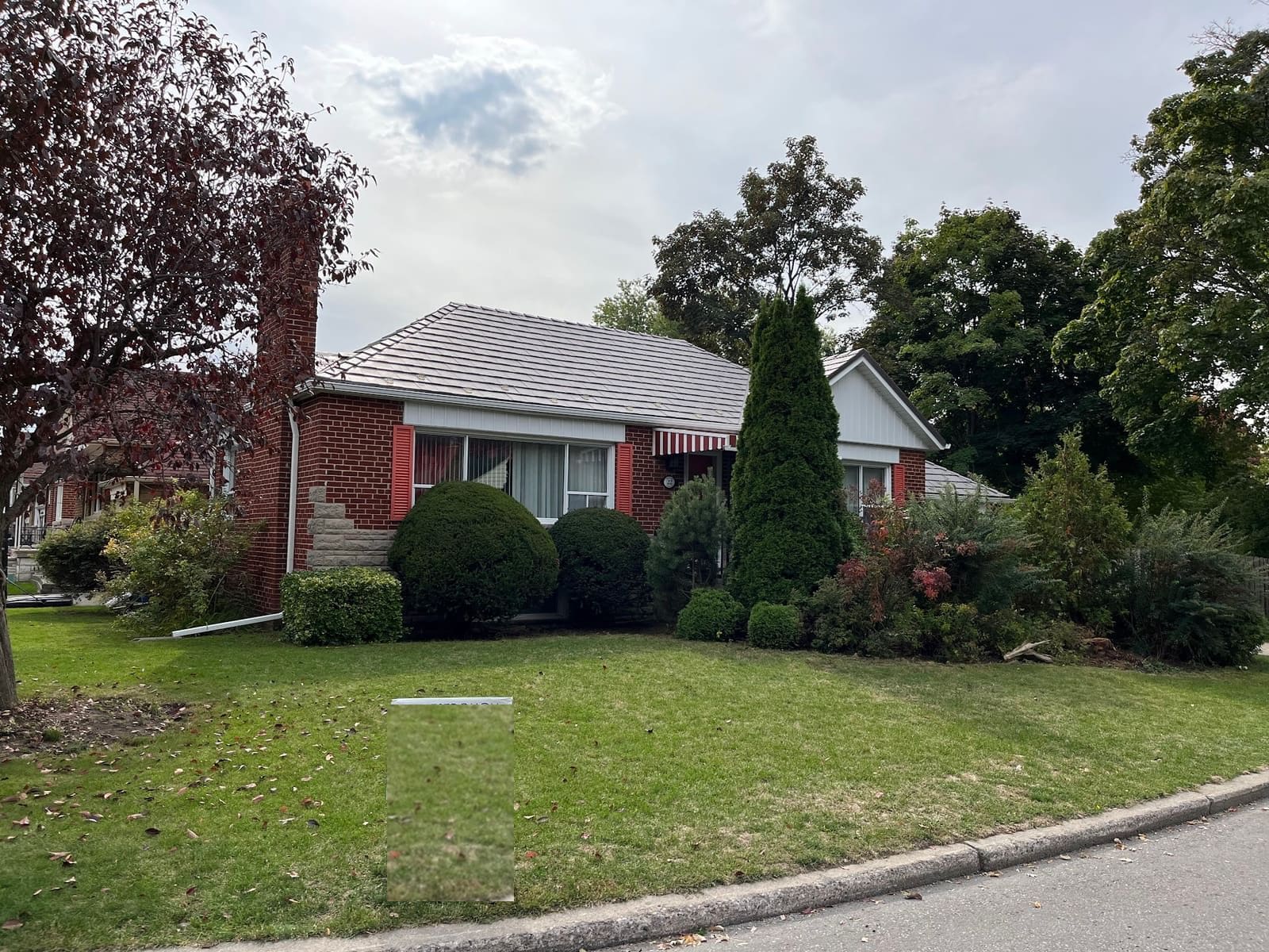 Brick bungalow with a new light-grey metal roof and white eavestrough