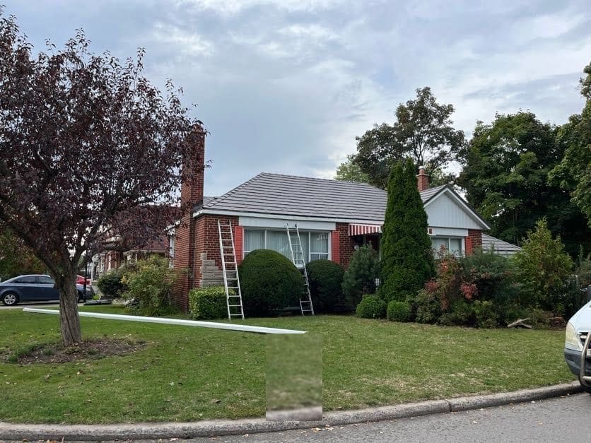 Eavestrough replacement in progress, with ladders and new gutter stock on the lawn