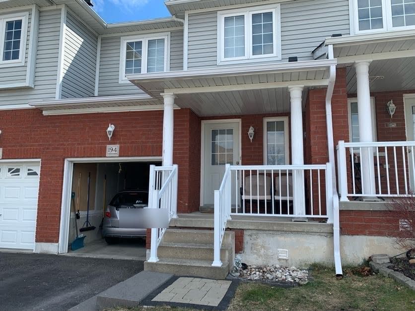 White downspouts and eavestrough on a finished brick townhouse